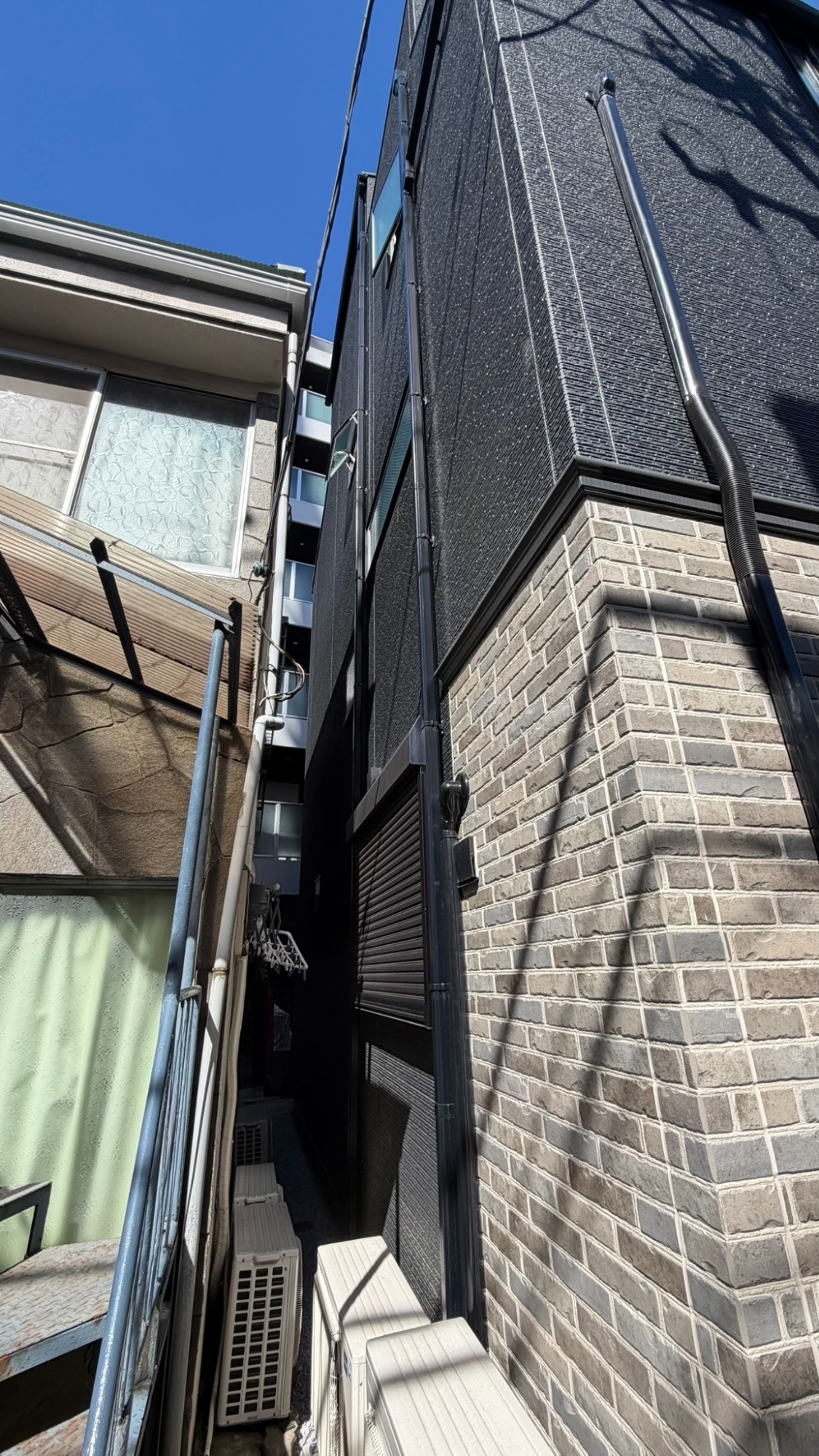 練馬区の新築3階建て住宅と隣接建物の間にある狭い作業空間
