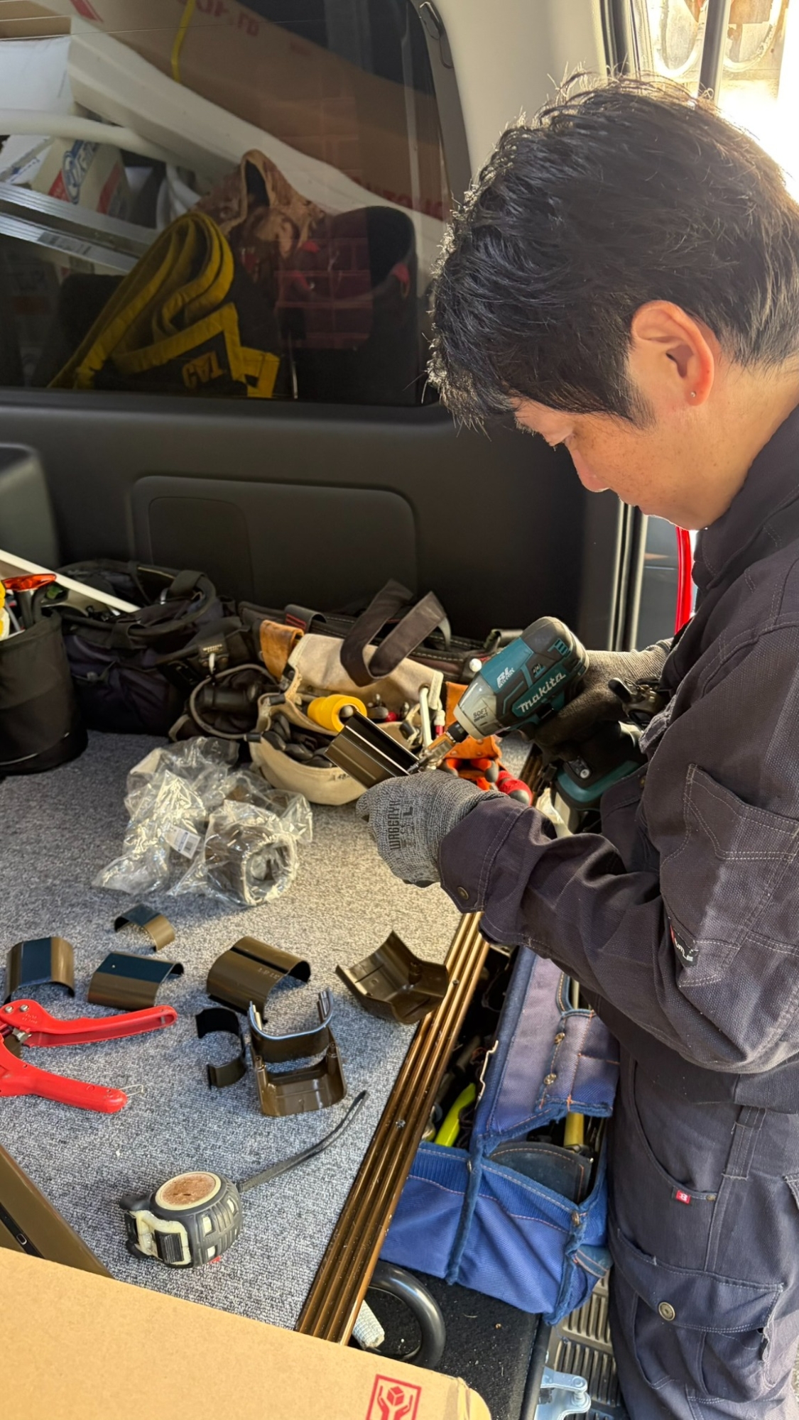 車両内の作業スペースでダクトの継手を加工している職人