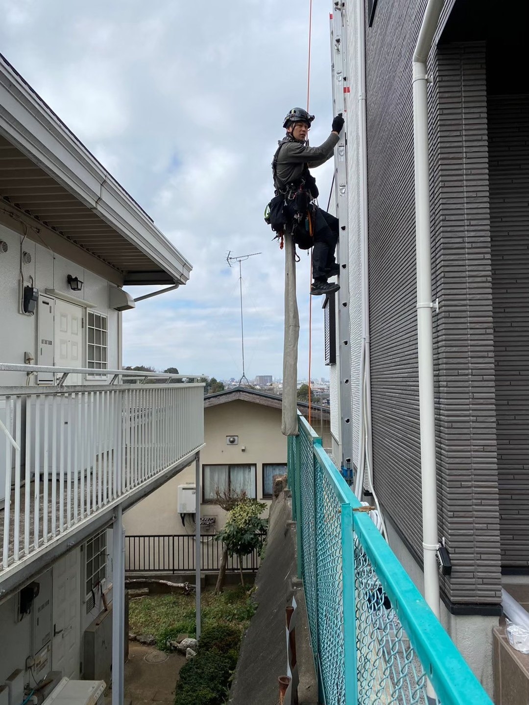 建物間の高所でロープアクセスにより施工位置へ入る職人です。