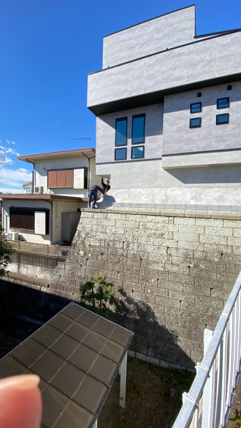 高い石積み擁壁の上に建つ住宅の高所エアコン工事現場