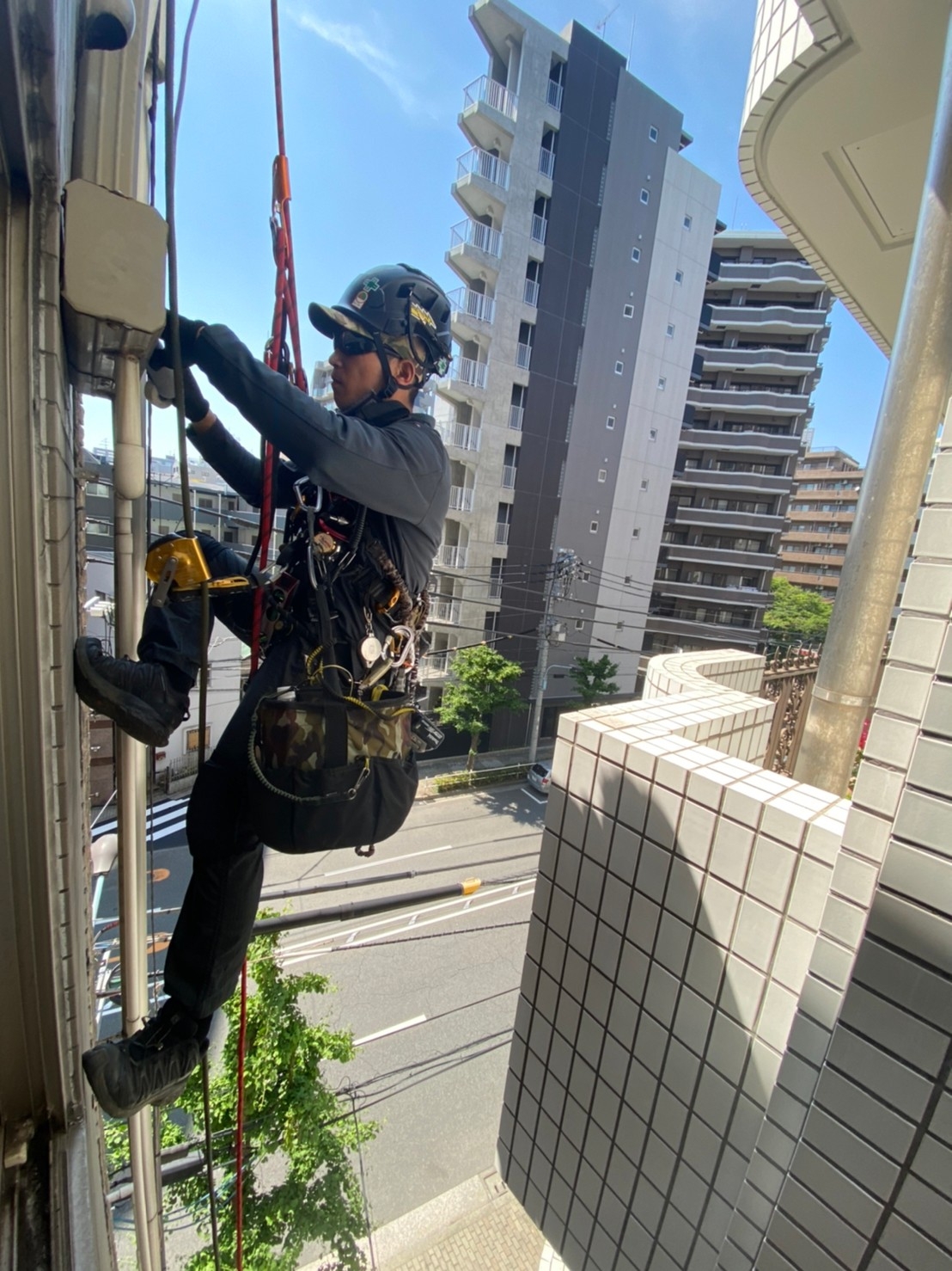 ヘルメットとフルハーネスを装着し、ロープに接続して施工する職人