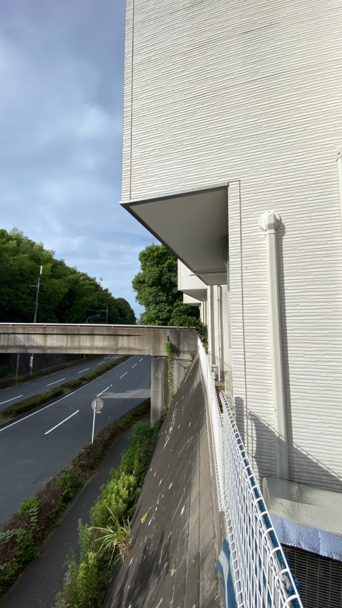 高い擁壁よりも外側へ張り出した住宅の外壁と道路までの高低差