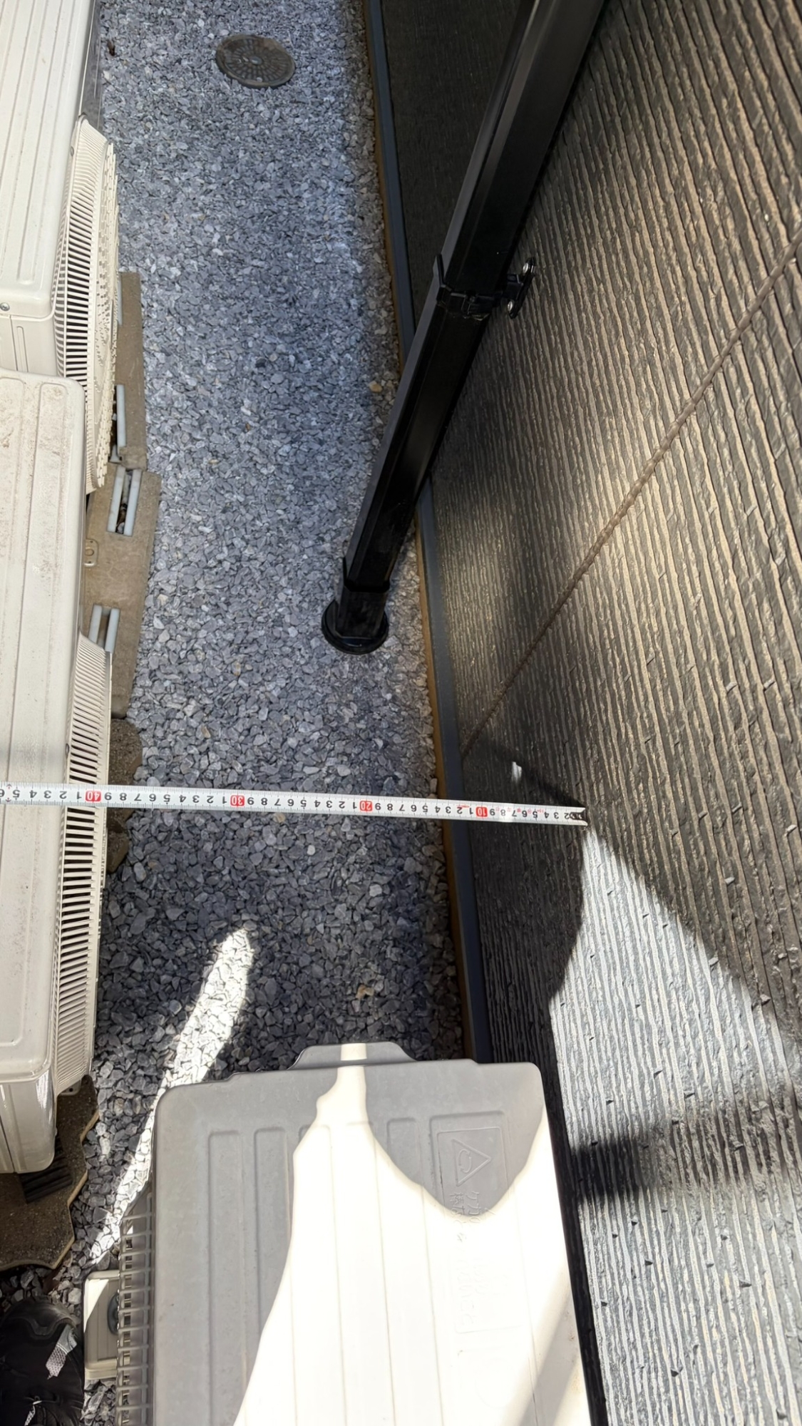 室外機などの設備が並ぶ側の通路をメジャーで測っている様子