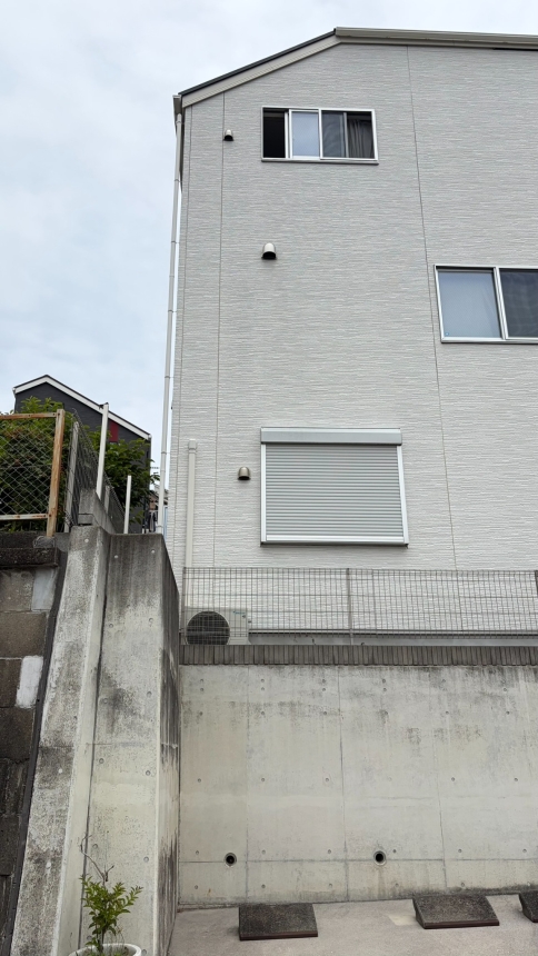 コンクリート擁壁上に建つ3階建て住宅の全景