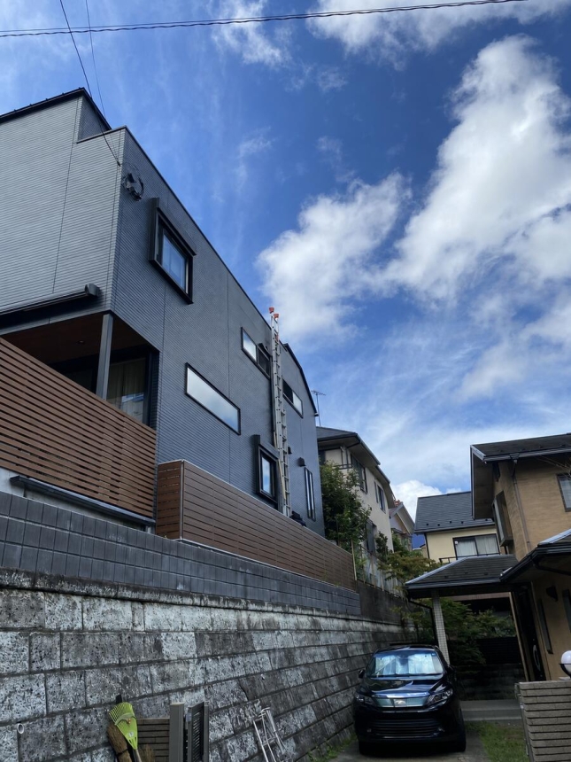 横浜市の擁壁上に建つ一戸建てと隣接車両の全景