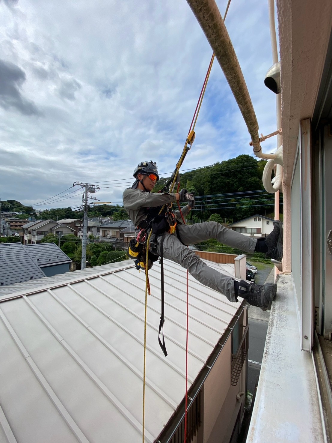 ロープで身体を保持して壁面作業を行う職人の足元