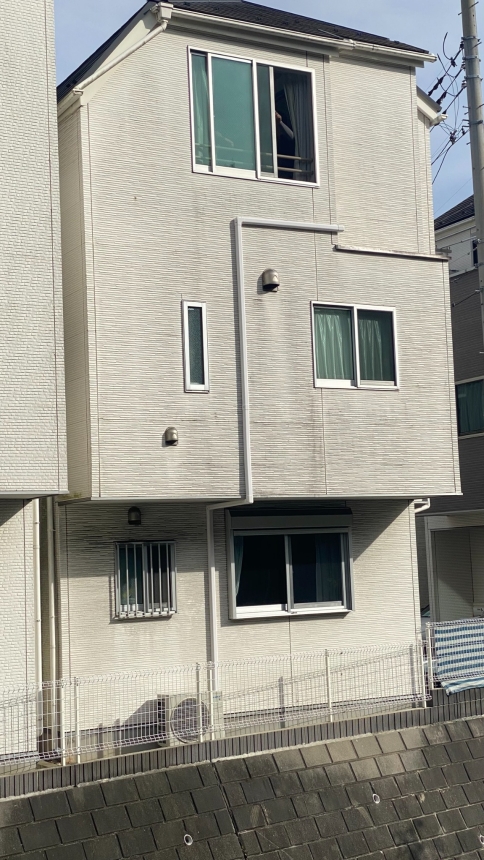 擁壁上の住宅で外部配管と室外機を納めていく施工の様子