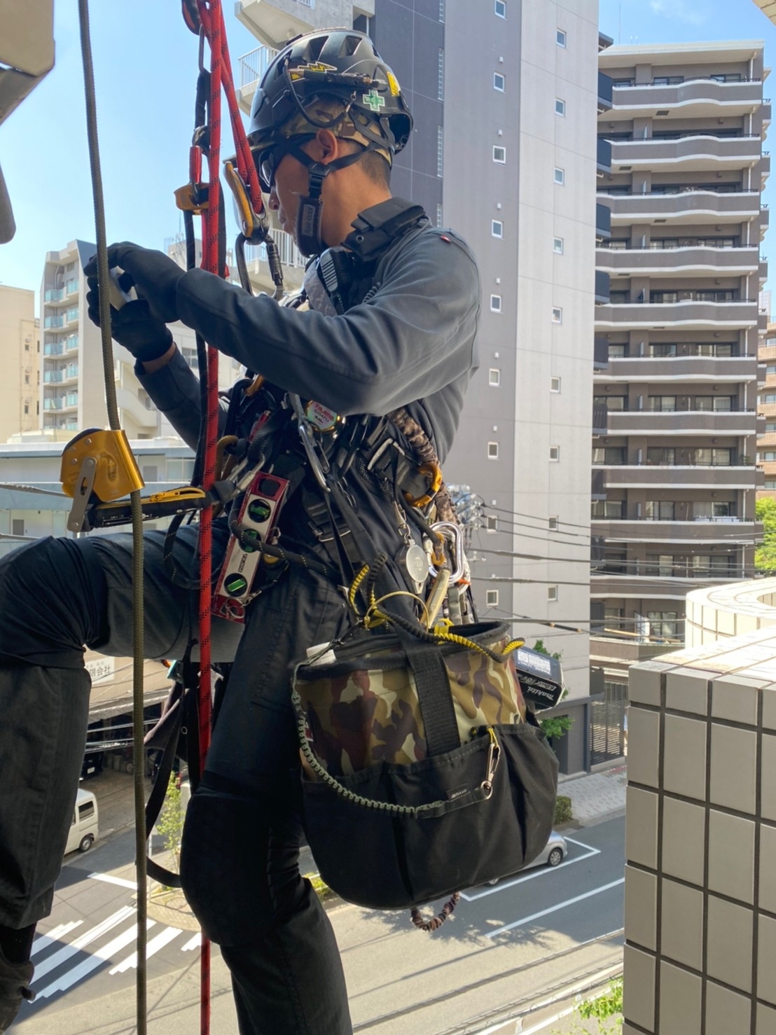 工具用バケツと落下防止ワイヤー、手で扱っているビニールテープ