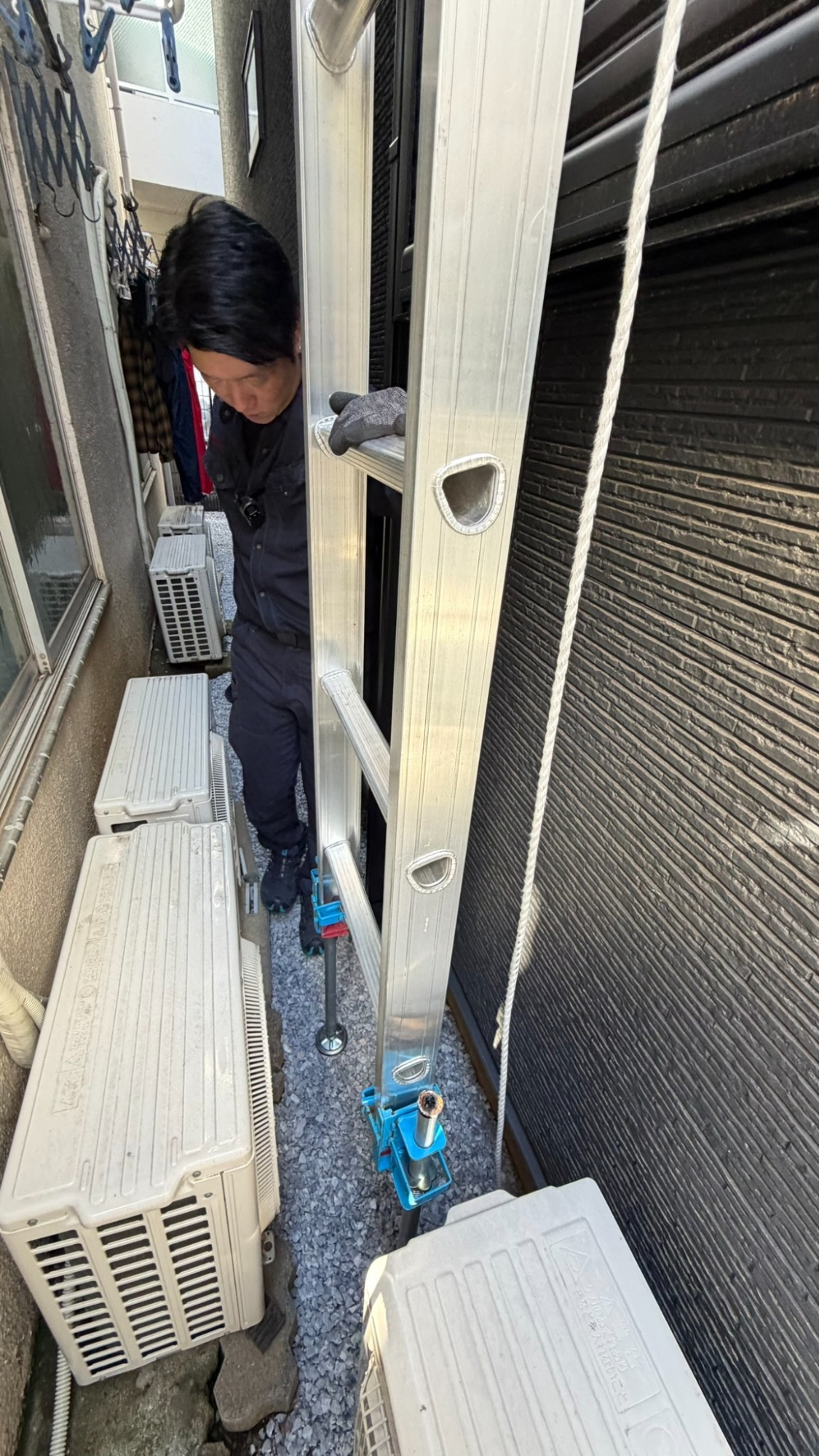 狭い建物間で垂直ハシゴのそばに立つ作業者