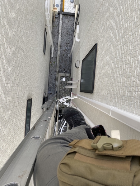 住宅同士の狭い隙間で垂直ハシゴを使用して高所エアコン工事を行うクアトロテクノサービス