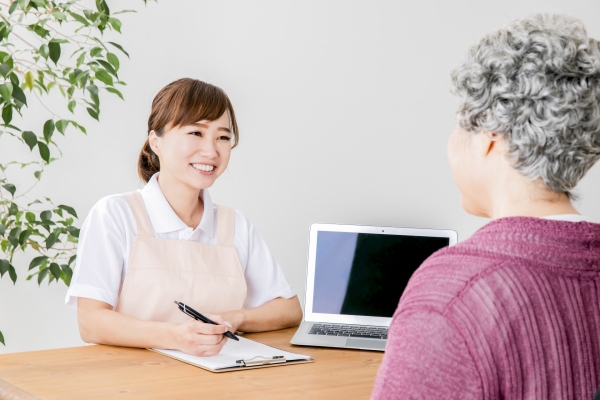 在宅のリビングでケアマネジャーがご家族にケアプランをわかりやすく説明している場面
